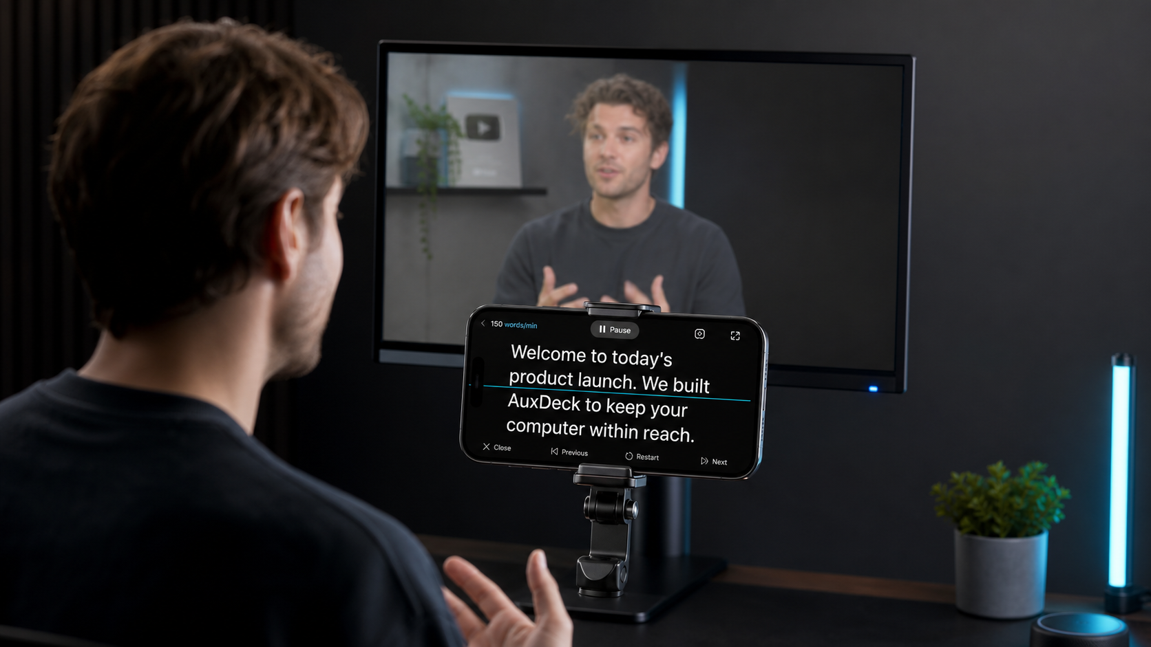 A mounted phone running the English AuxDeck teleprompter below a computer monitor